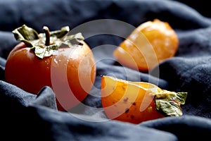 Slices of Orange red persimmon fruit.Fresh kaki on classical blue cloth.