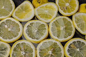 Slices of organic Sicilian lemon arranged on a glittered black glass background