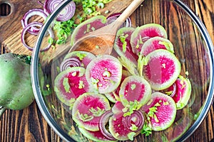 Slices pink fresh watermelon radish onion and celery homemade carpaccio salad for delicious breakfast on wooden table selective fo
