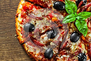 Pizza with Mozzarella cheese, salami, pepper, ham, pepperoni, olives, Spices and Fresh Basil. Italian pizza on wooden background