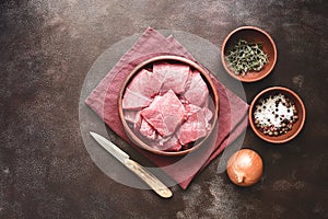 Slices of raw fresh beef meat with spices and herbs on a dark rustic background. Top view, flat lay, copy space