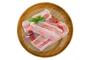 Slices of raw fresh pork belly cut on wooden plate isolated on w