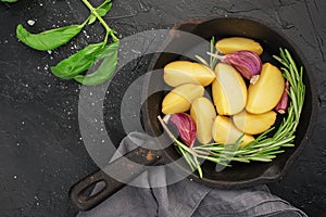 Slices of raw fresh potatoes before cooking with basil, rosemary, butter, garlic and salt for baking in country style