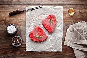 Slices of raw roast beef on white cooking paper and wooden table