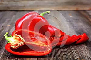 Slices of red bell pepper on a wooden background