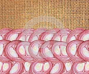 Slices of red onion over burlap linen background