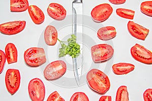 Slices of red ripe tomato on a white background on the kitchen. Tomato divided in half, steal knife on the center.