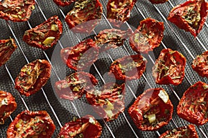 Slices of red tomatoes sun-dried arranged on metal grid. Healthy vegetarian food