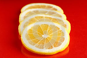 Slices of ripe bright lemon on a red background.