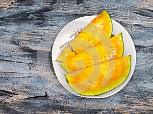 Slices of ripe yellow watermelon on a light plate top view