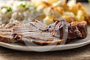 Slices of roasted neck with potatoes and rice on a plate - Close up