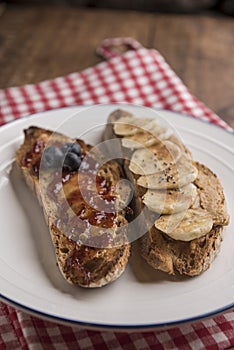 Slices of rustic bread with peanut butter, banana and strawberry jam