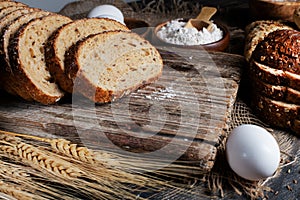 slices of rye bread, ears of wheat, eggs and a bowl of flour. Close-up