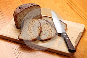 Slices of rye bread and a kitchen knife on a cutting board