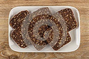 Slices of rye bread with sunflower seeds in plate on table. Top view