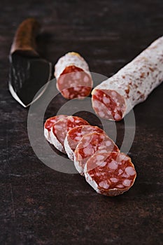 Slices of salami sausages on dark background