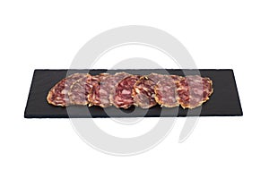 Slices of salchichon iberico as a tapa in a slate plate on a white background