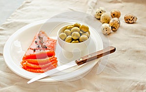 Slices of Salted Raw fish fillet with olive, quail eggs on white plate. Selection of good fat sources - healthy eating concept.