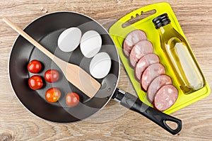 Slices of sausage, vegetable oil on cutting board, frying pan