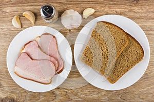 Slices of smoked gammon in plate, bread, garlic and pepper
