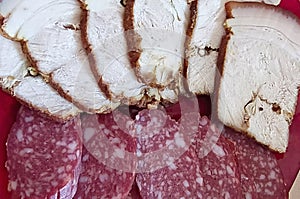 Slices of smoked sausage and boiled pork lie on a plate. Close-up, selective focus
