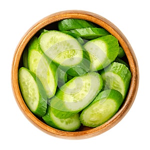 Slices of snack cucumbers, diagonally cut cucumber fruits, in wooden bowl photo