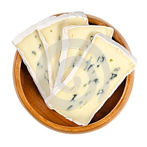 Slices of soft cheese with white and blue mold in wooden bowl