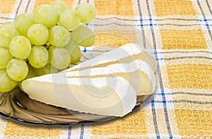 Slices of a soft cheese and white table grapes closeup