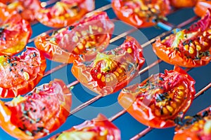 Slices of sun-dried tomatoes with spices on a metal wire rack in the oven. Close-up. Macro