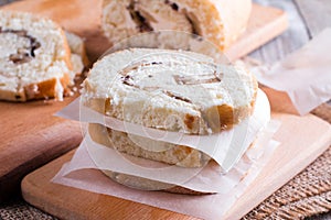 Slices of sweet cream roll with parchment paper on a cutting board