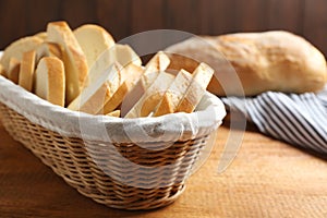 Slices of tasty fresh bread in wicker basket on wooden table