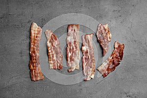 Slices of tasty fried bacon on dark background