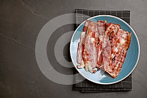 Slices of tasty fried bacon on dark table. Space for text