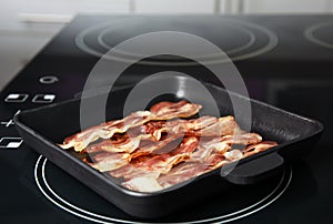 Slices of tasty fried bacon on stove