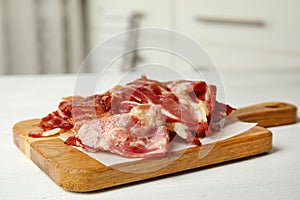 Slices of tasty fried bacon on white wooden table