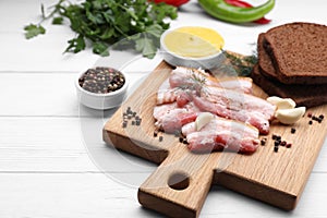 Slices of tasty pork fatback with garlic, rye bread and sauce on white wooden table, closeup