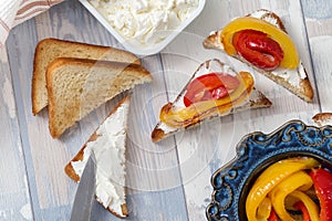 Slices of toasted bread with white soft cheese and fried bell peppers