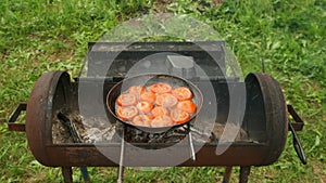 Slices of tomates is frying on frying pan with oil in chargrill, top view.