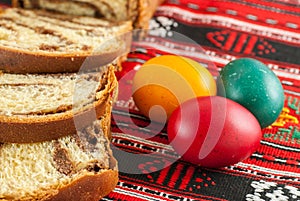 Slices of traditional easter sweet bread or cozonac and colored eggs, romanian easter