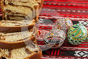 Slices of traditional easter sweet bread or cozonac and traditdional decorated eggs, romanian easter dish