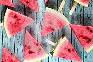 Slices of water-melon on popsickle stick on blue wooden background flat lay