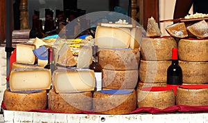Slices and wheels of Pecorino cheese together with bottles of Cannonau, white wine, pasta and other Sardinian typical dishes