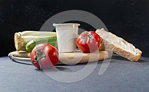 Slices of white beautiful airy white bread, yogurt, fresh vegetables - cucumbers, tomatoes and celery, all on a round wooden