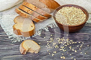 Slices of whole-wheat bread with wheat seeds on a wooden background