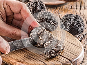 Slicing of black winter truffles. Black truffles and truffle slices on wooden board