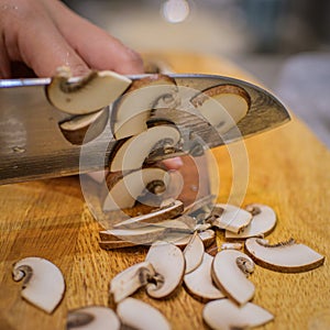 Slicing brown button mushroom with a santoku chef knife. photo