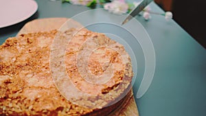 Slicing a cake of oatmeal and apples under a caramel crust