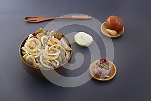 Slicing fermented green tomatoes and cucumbers with onions pickled garlic in a wooden bowl