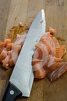 Slicing fresh smoked salmon on a wooden cutting board with a kitchen knife