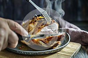 Slicing hot roasted pork with steam